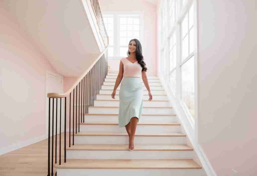 Dark haired lady walking down the stairs to represent how small steps add up